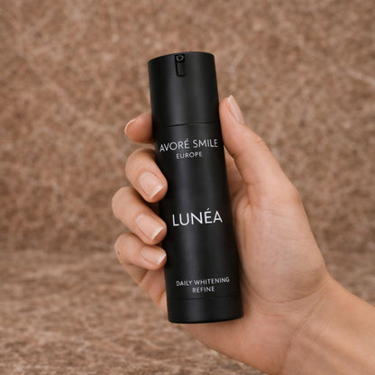 Hand holding Avoré Smile Lunéa bottle against stone background